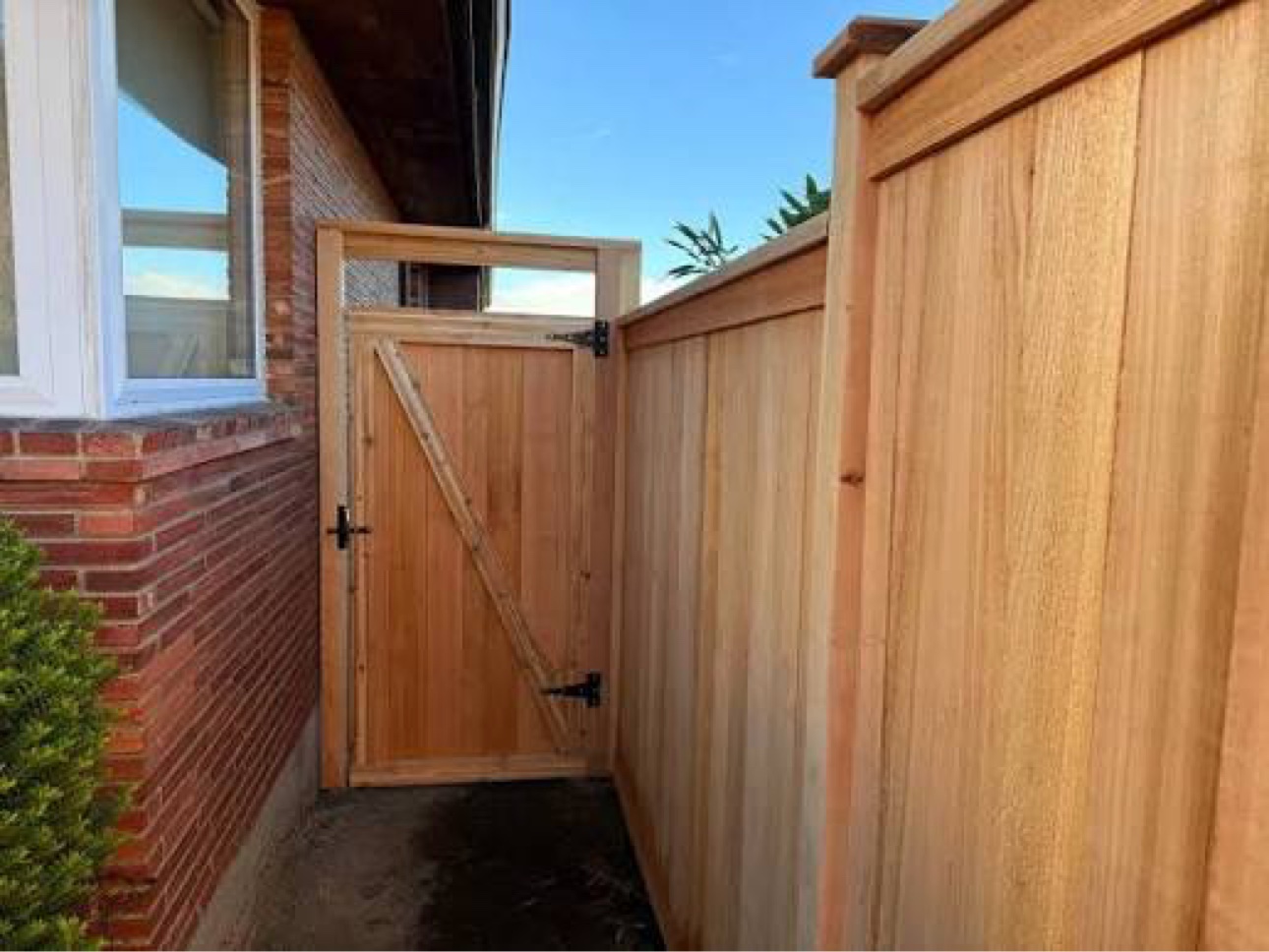 Wooden side gate with diagonal bracing beside brick home